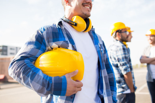 close up of builder holding hardhat at building